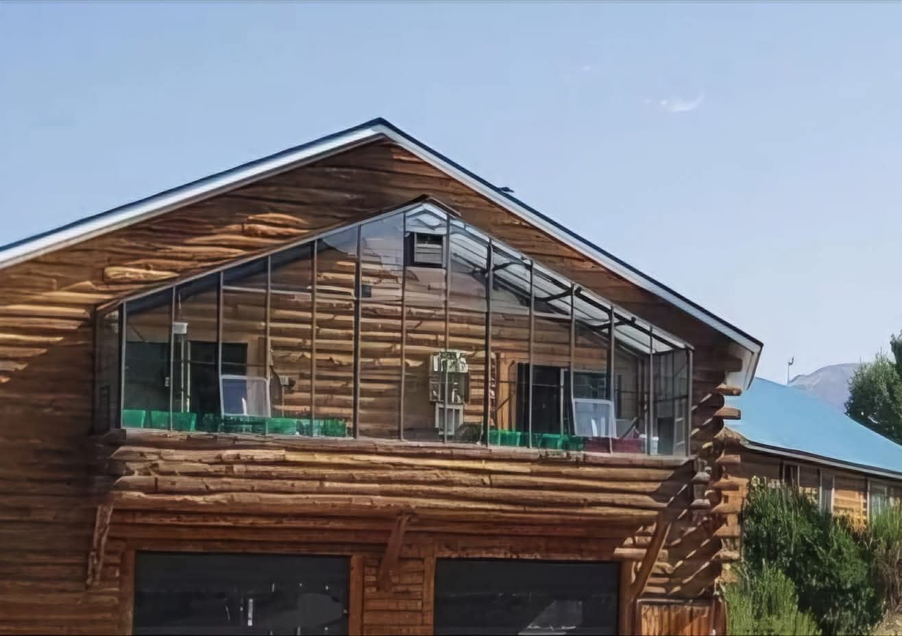 The peaked glass solarium attached to the second story of the log home